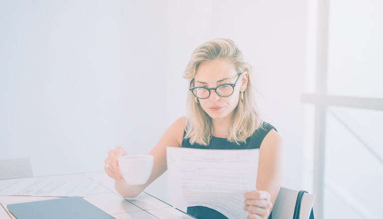 mujer tomandose un cafe mientras mira unos documentos sobre si hay que declarar una indemnizacion por accidente de tráfico